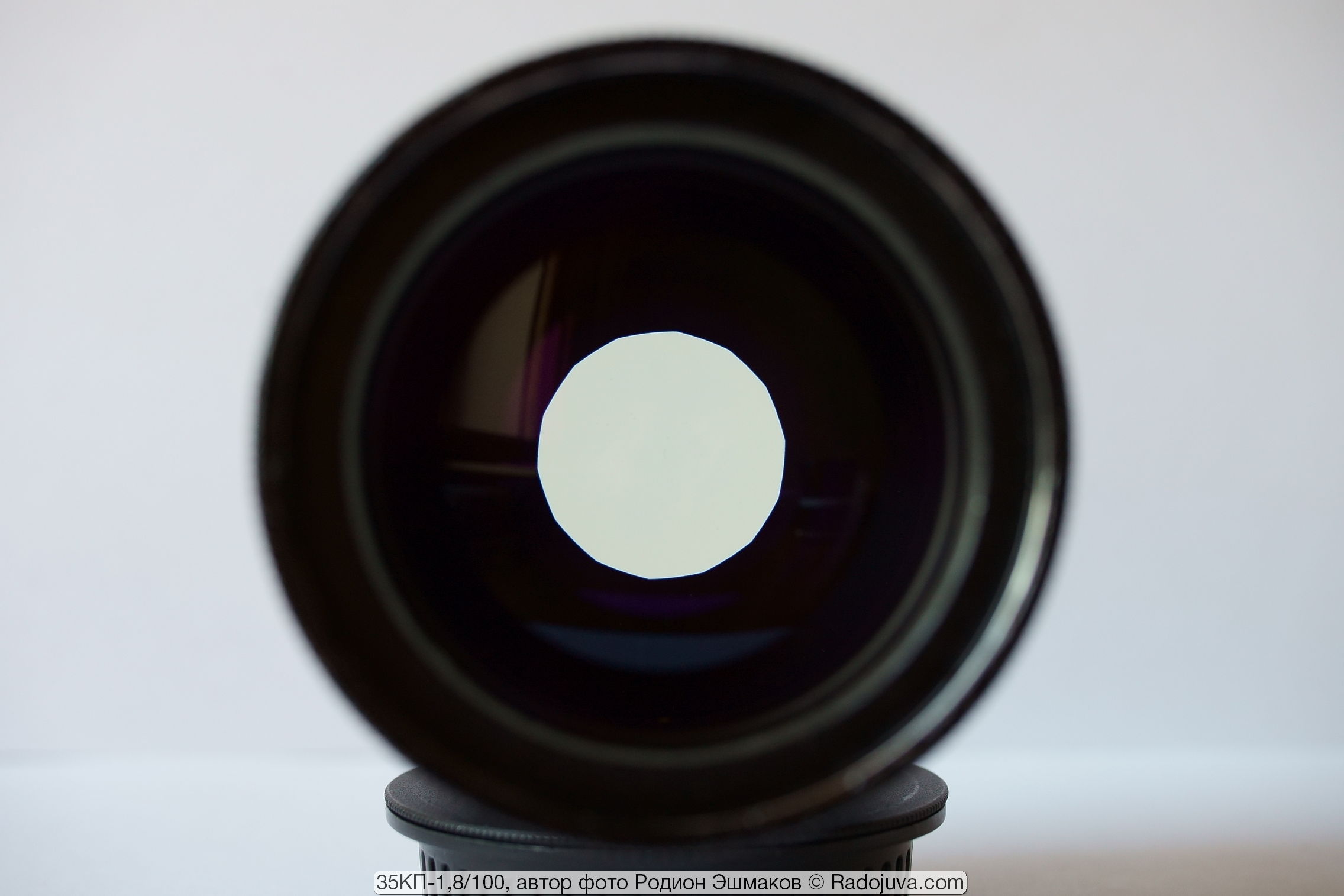 View of a round opening of a covered fourteen-blade diaphragm in the light. Yellow tint of lenses is noticeable.