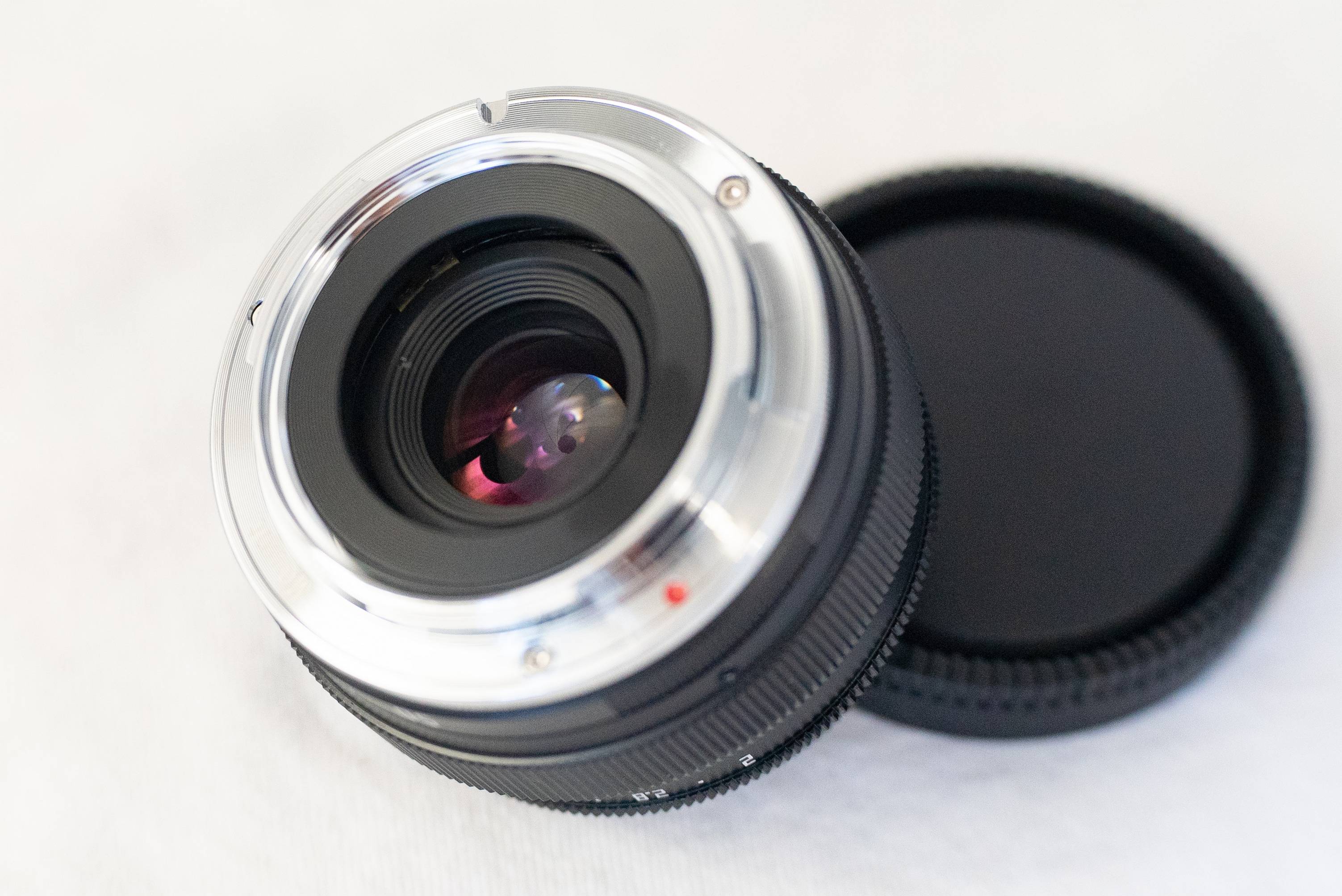 Zicht op de lens bij scherpstellen op MDF vanaf de zijkant van de achterlens. Op 10 uur van de voorwaardelijke wijzerplaat is een messing deel met een dunne geleider zichtbaar waarlangs het lensblok van de lens beweegt.